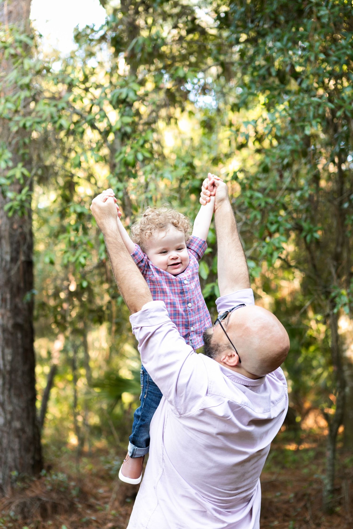 joyful outdoor playtime with a child being lifted up high in a wooded setting. Orlando Family Photography, Sanford Family Photography
