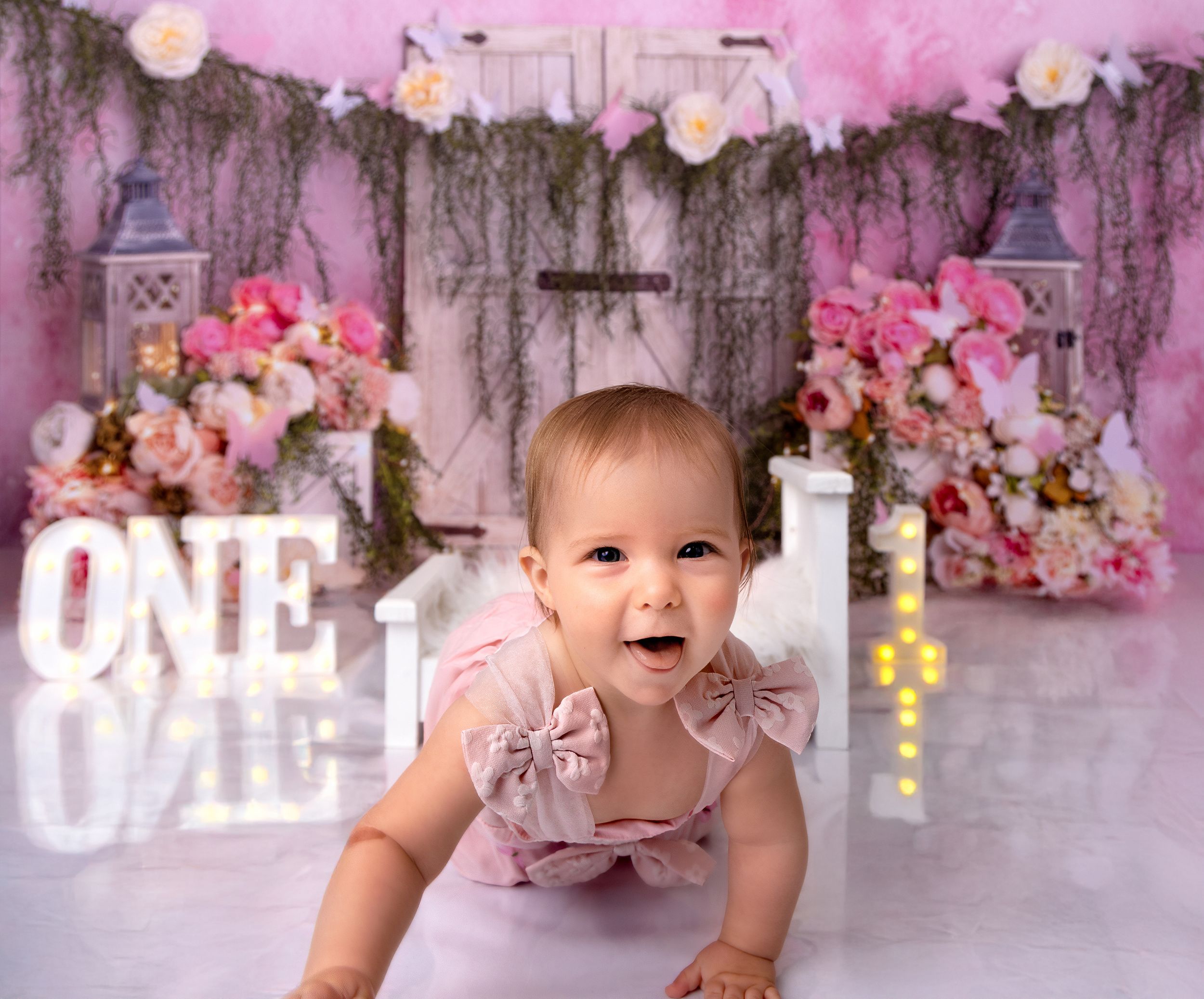 Baby in pink floral dress crawls and poses against pink floral backdrop in milestone photo collage.