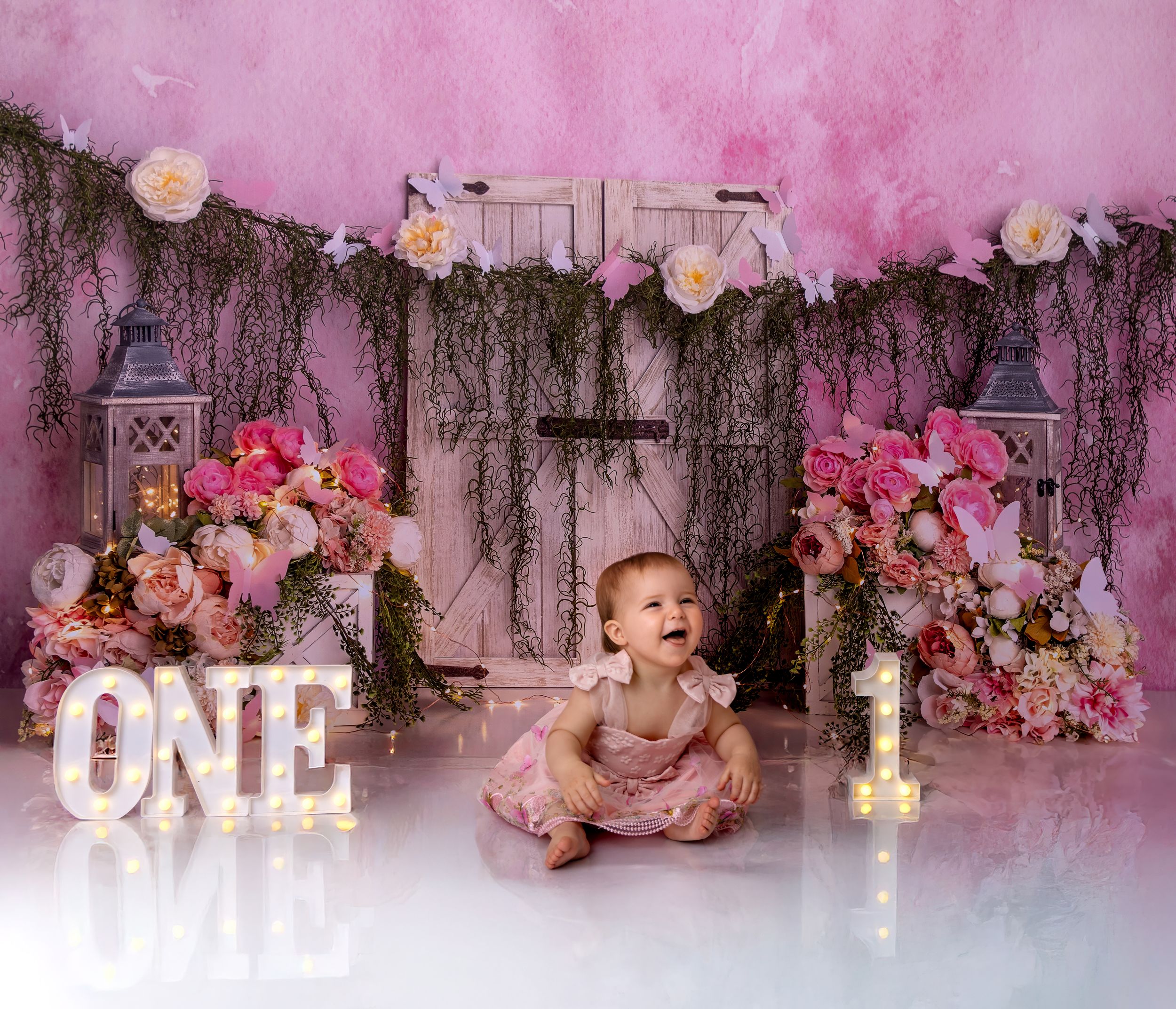 Pink floral backdrop with rustic wooden panels and white decorative letters creating a romantic photography setting.