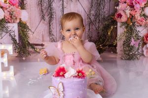 Pink floral decorations and props create a whimsical backdrop for a baby photography session.