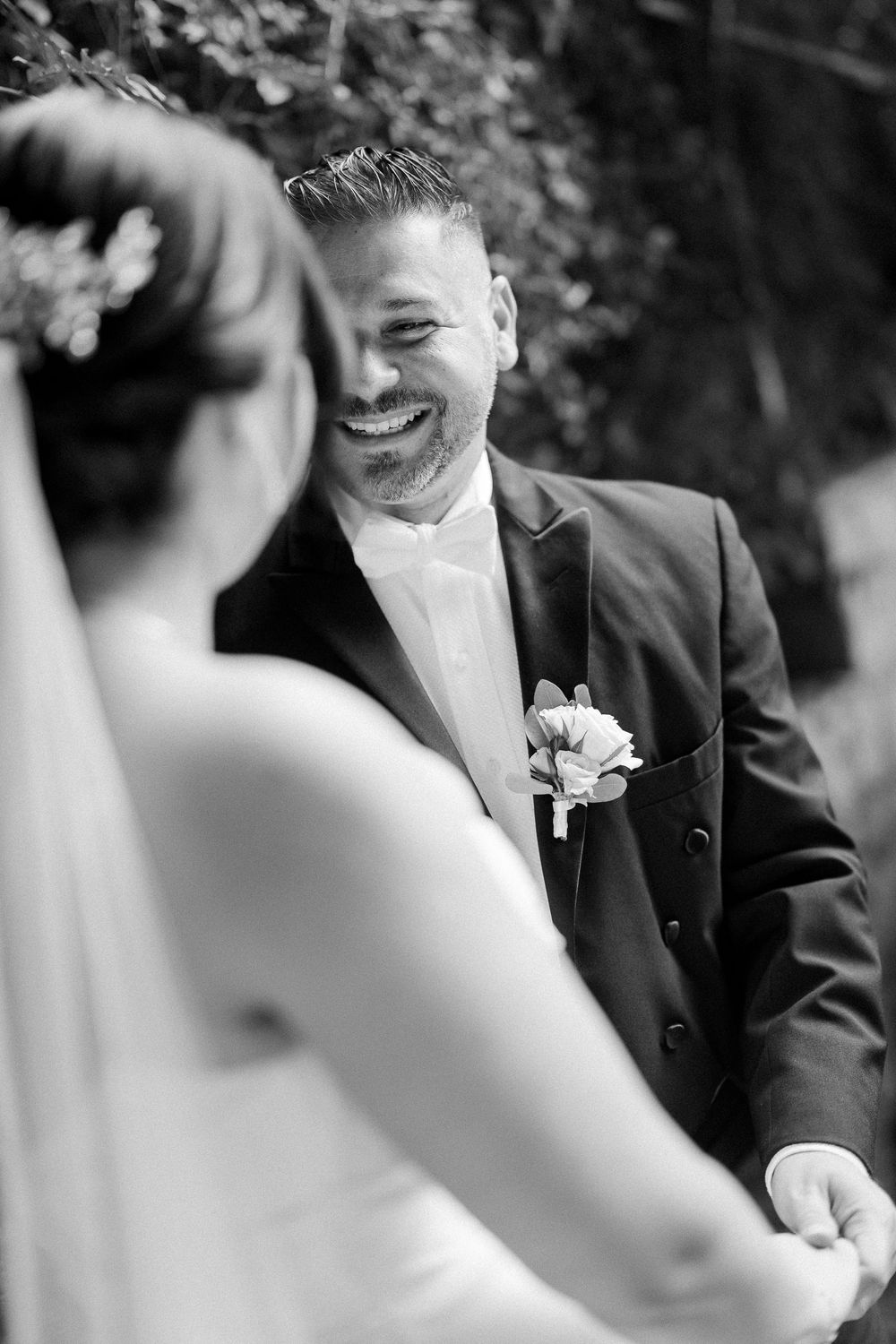 A candid black and white moment captured during an outdoor wedding ceremony showing joyful expressions.