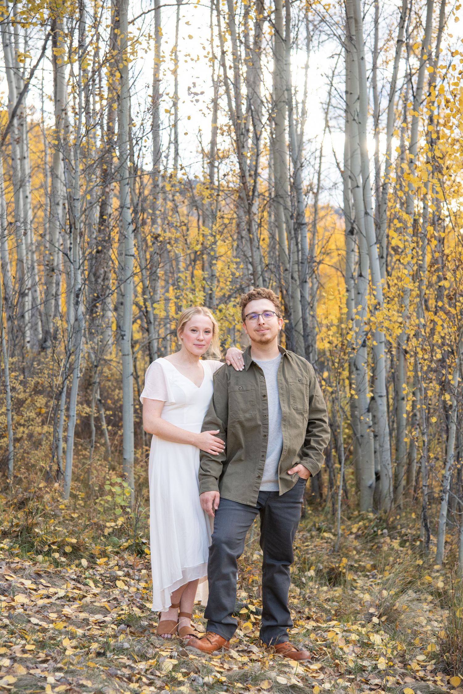 Vail engagement photos with beautiful couple standing in a forest of yellow leaves and aspen trees in the fall
