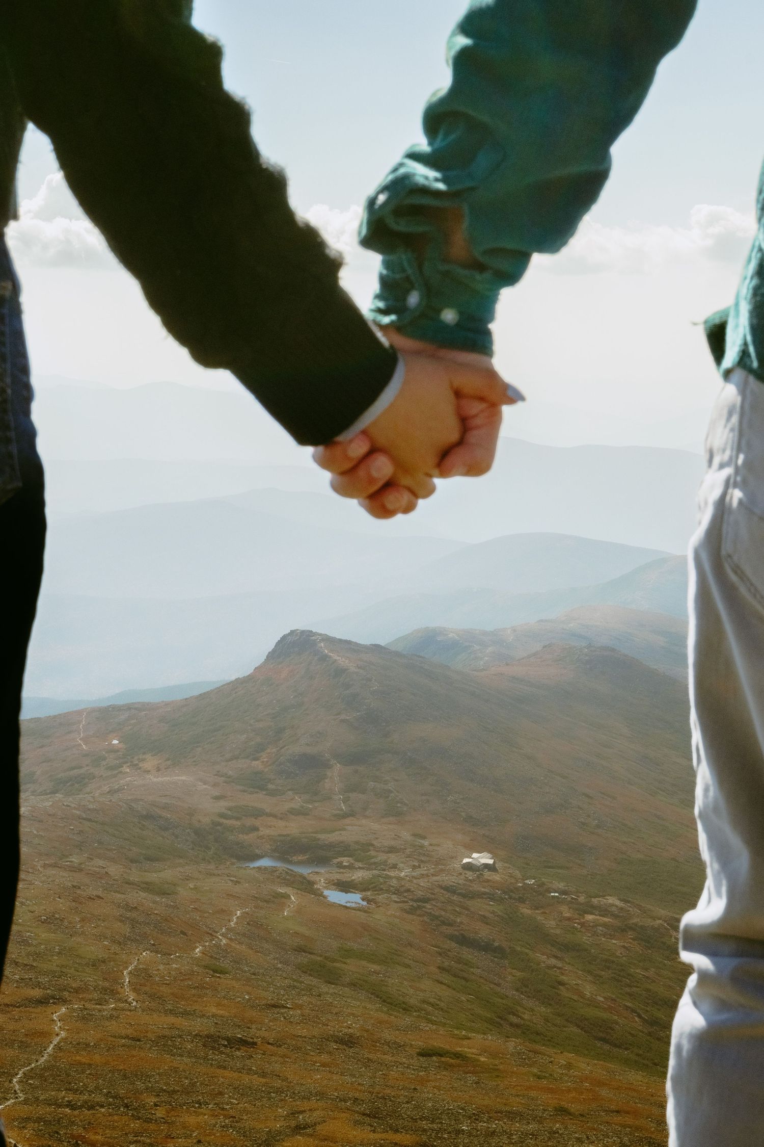 Memory Lane Studios couple holding hands overlooking vast Mt Washington mountainous landscape engagement photography by Tharun Palla