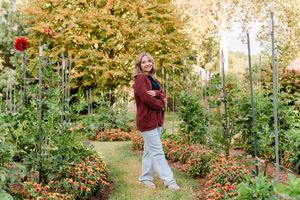 A scenic garden path lined with vibrant orange and red roses in full bloom during autumn.