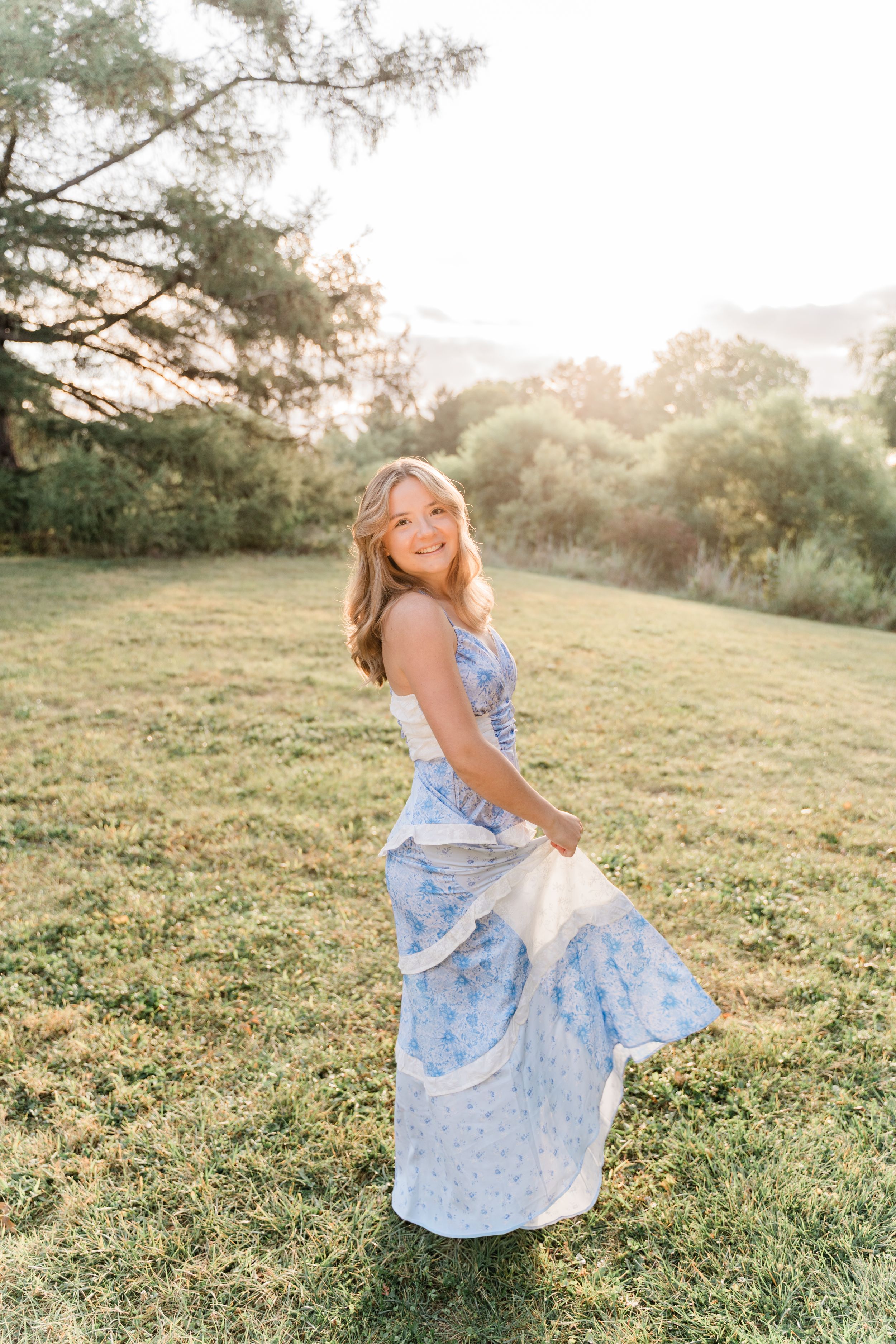 A light blue floral dress twirls gracefully in a sunlit meadow during golden hour.