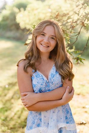 A series of outdoor portrait photos in a light blue floral dress with golden sunlight filtering through trees in the background.