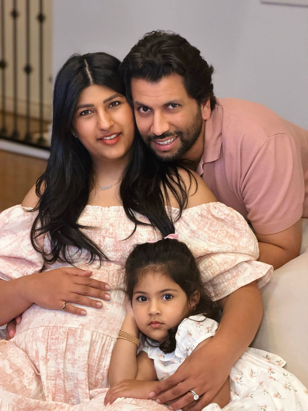 A family in matching pink outfits poses together for a series of intimate portrait photographs.