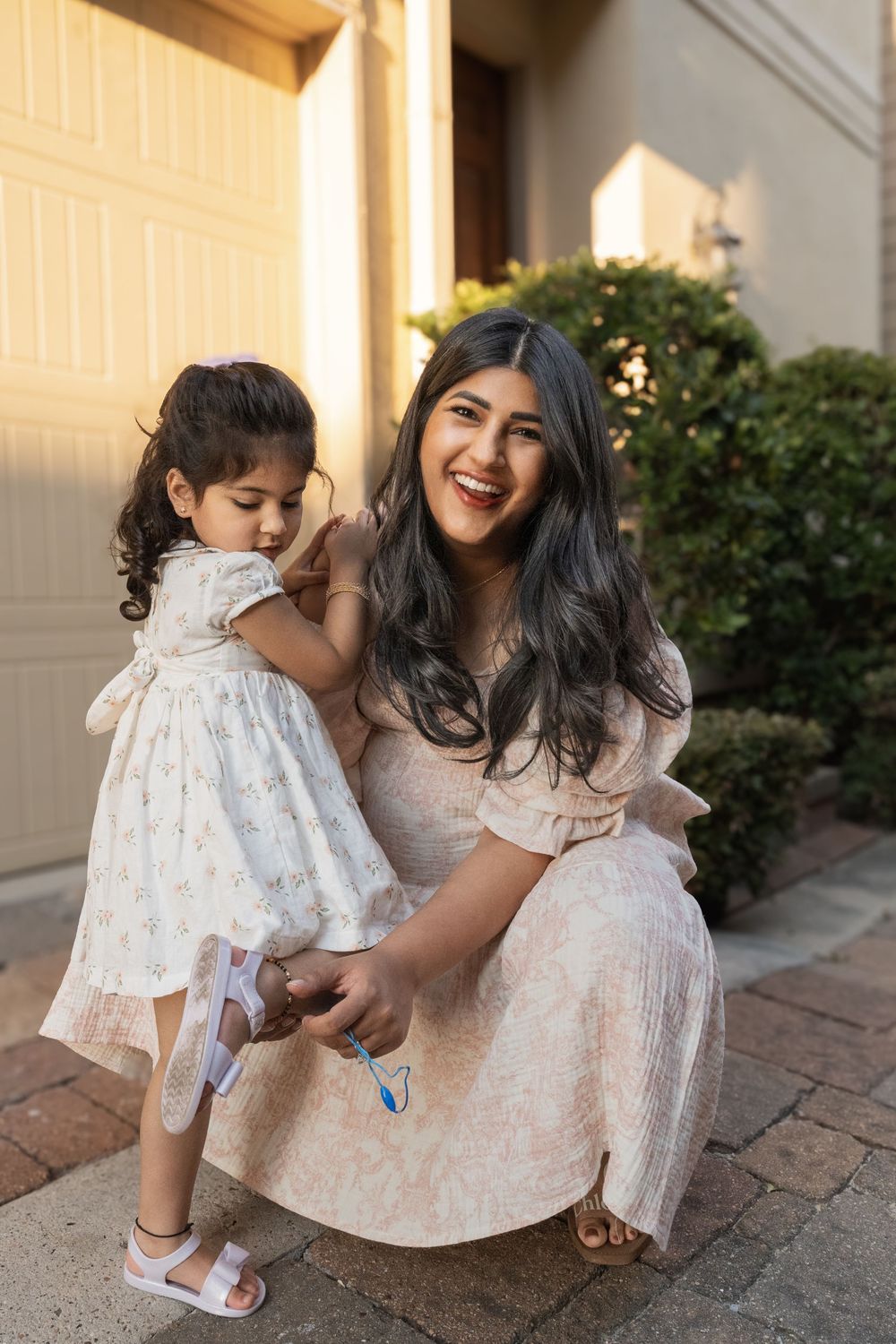 Mother and toddler sharing sweet moment together on brick pathway outside.