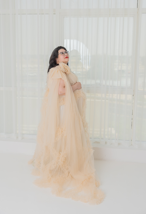 Ethereal maternity photos with flowing champagne colored gown in bright white room.