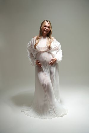 Four connected images show a flowing white pleated dress photographed against a light background in an ethereal style.