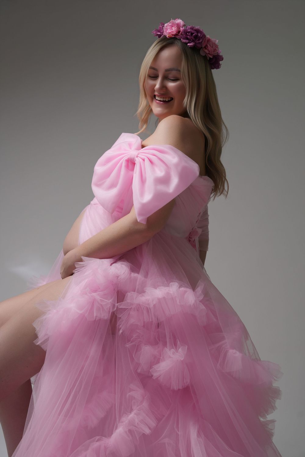 A person wearing a voluminous pink tulle dress with puff sleeves poses gracefully in a studio setting.