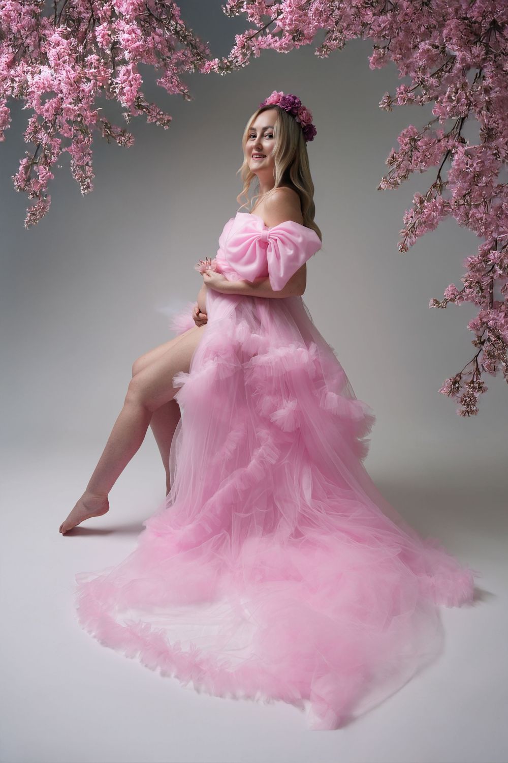 Ethereal pink dress flowing gracefully beneath blooming cherry blossom branches in a studio setting.