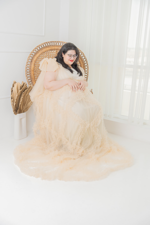 Glamorous maternity boudoir session on vintage chair with champagne colored tulle dress.