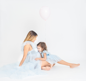Mother and child maternity photos in matching light blue outfits.
