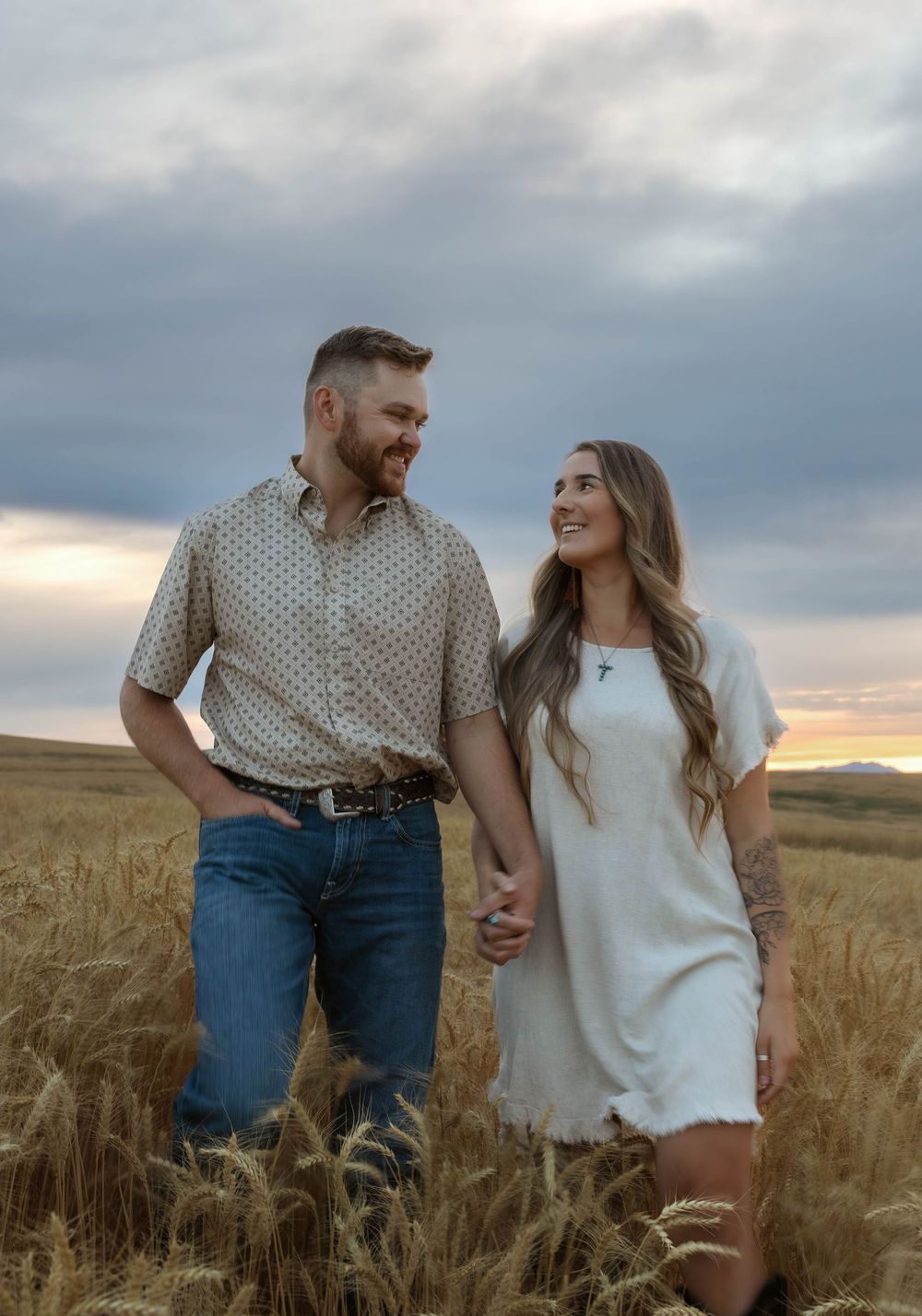 Candid couple photos taken in a rural wheat field during golden hour.