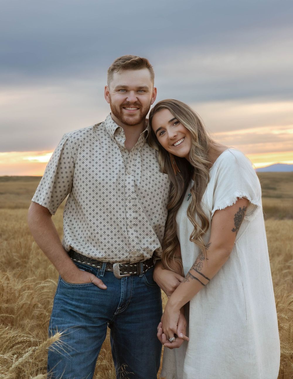 Sunset photoshoot of a couple holding hands in a rural wheat field.