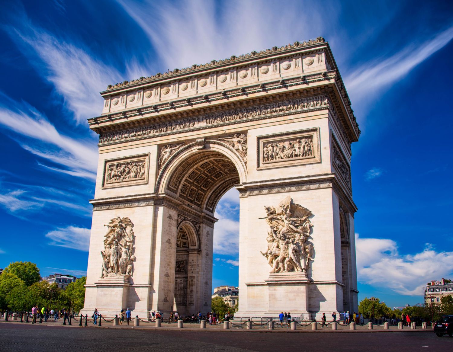 The iconic Arc de Triomphe monument in Paris shown from different angles against a vibrant blue sky with wispy clouds.