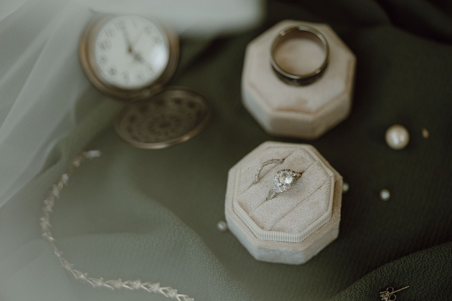 Close-up of vintage-style wedding accessories and jewelry on dark background.