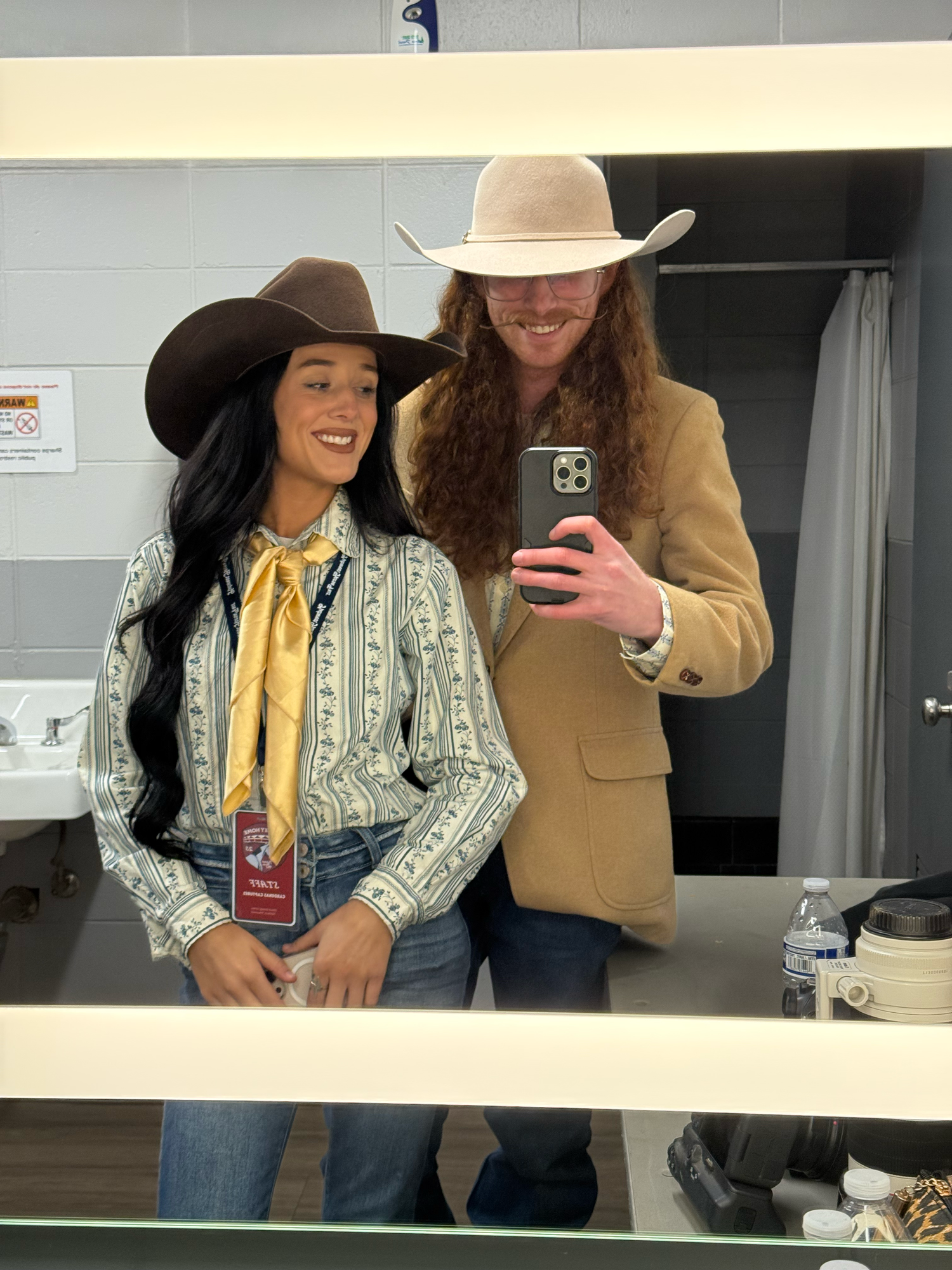 Two people in western outfits taking mirror selfies in a dressing room. Wisconsin Pro Rodeo PRCA Rodeo Photographer Dakota Cardenas