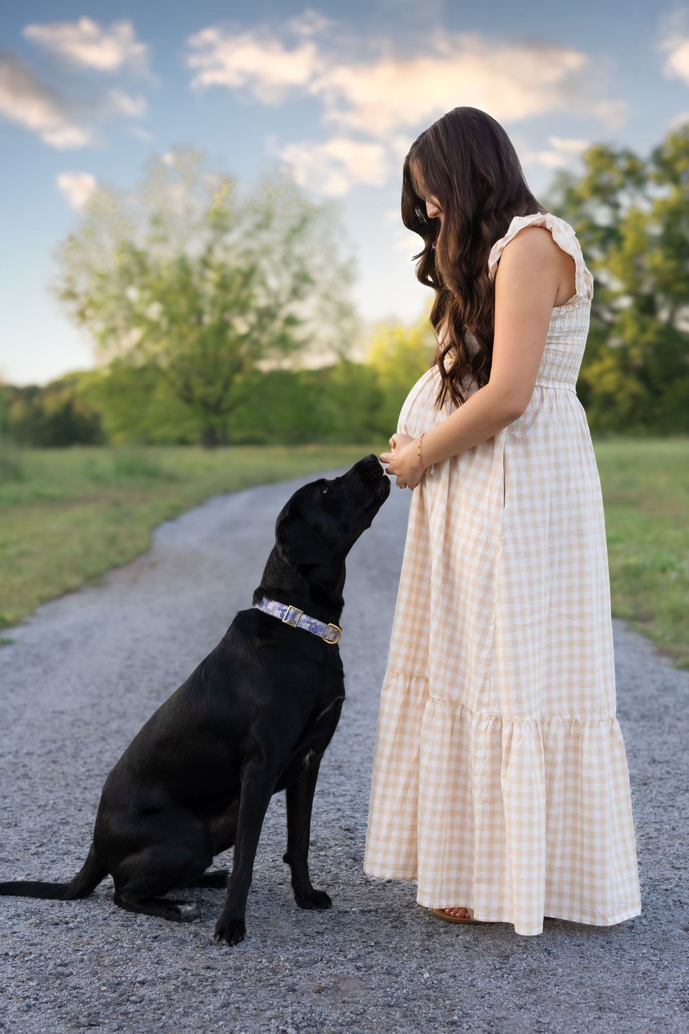 Mother-to-be with her dog standing on gravel path during maternity photography session in Watkinsville