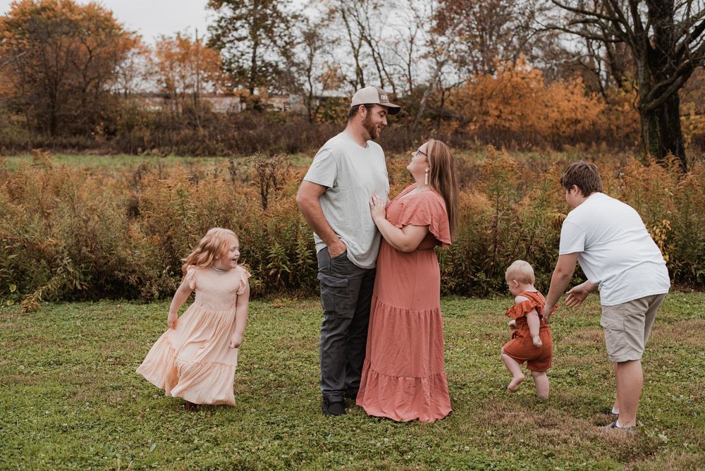A family of five running and playing together in a field at home.
