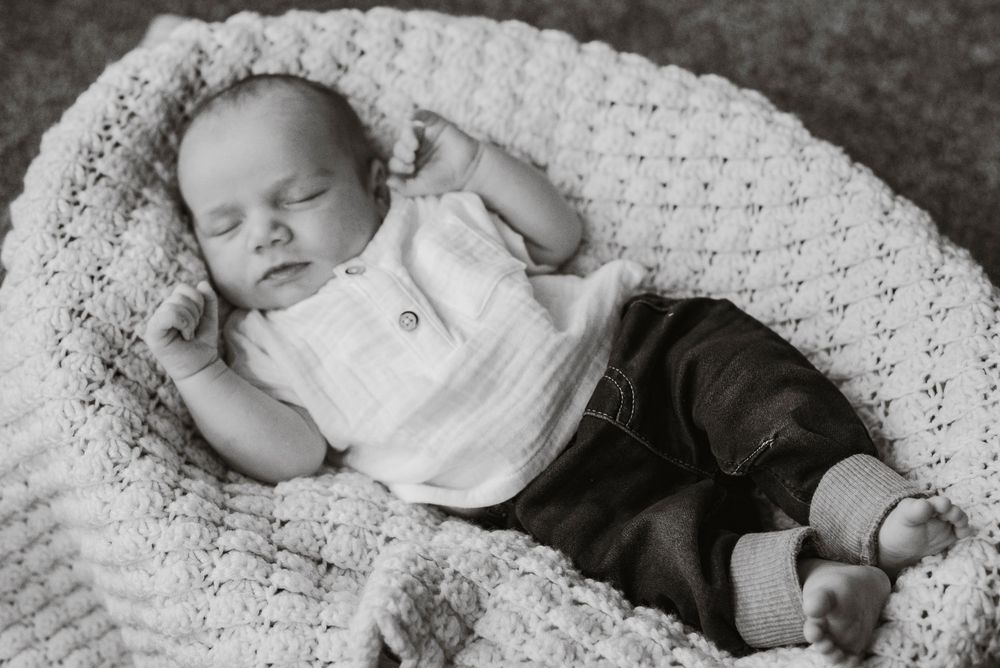 An infant in a basket with a blanket at home.