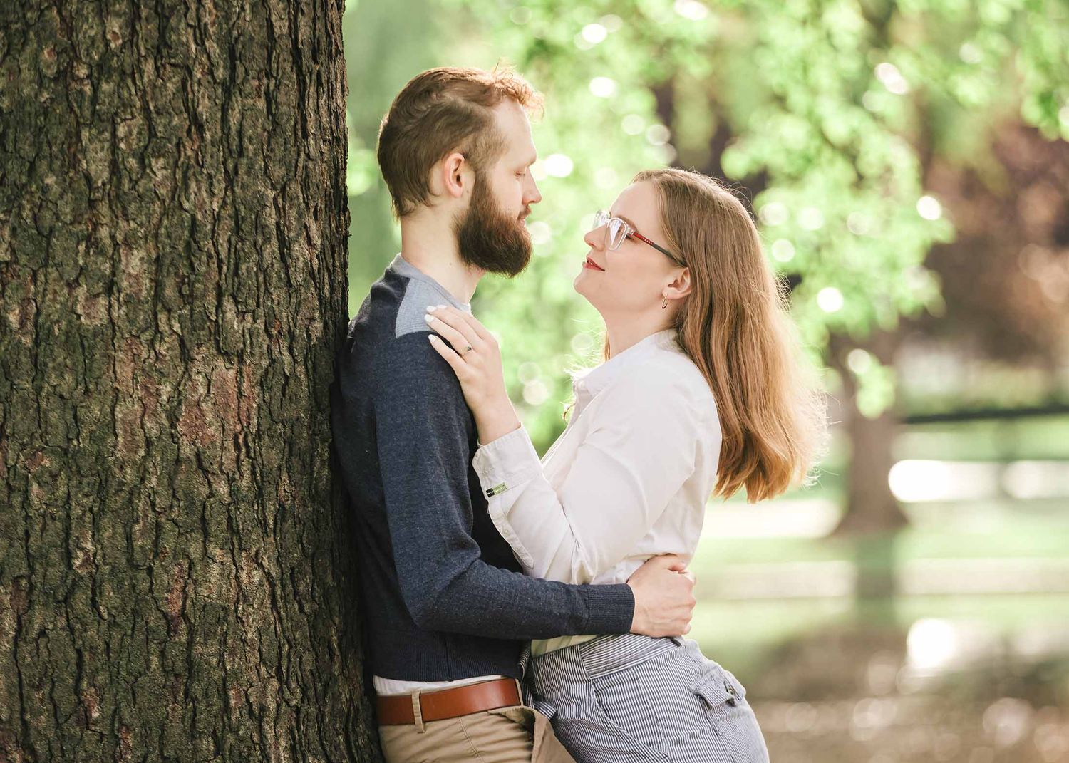 Engaged couple embracing beneath tree branches by the Lagoon in Boston Public Garden during dreamy early morning engagement session