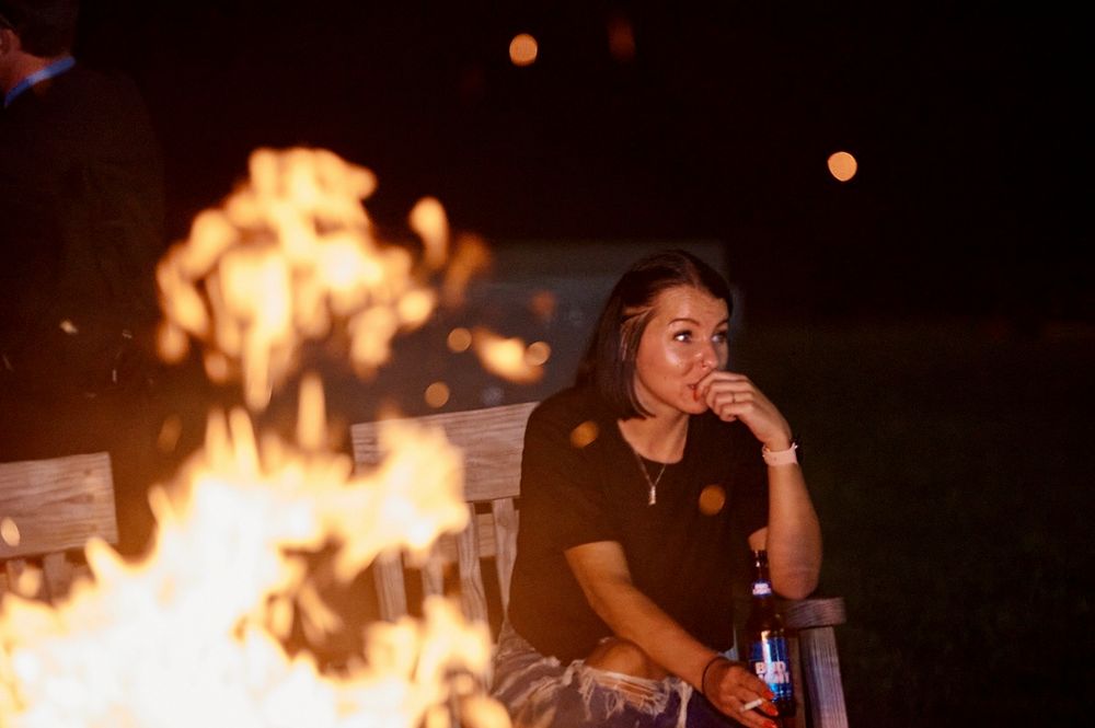 Atmospheric photo of woman standing near a bonfire at Blue Ridge Mountains wedding.
