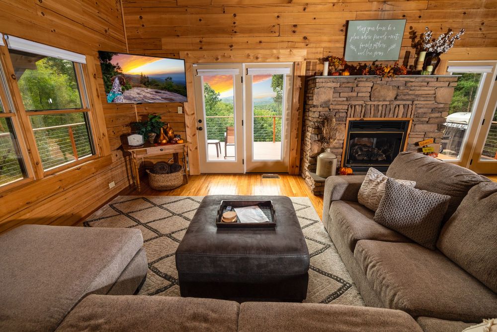 Spacious log cabin living room with comfortable sectional sofa and large windows overlooking nature.