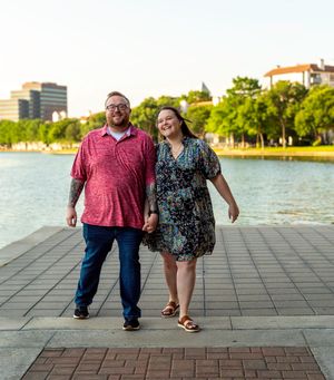 Couple walking along waterfront path with urban skyline in background. proposal engagement fort worth dallas texas