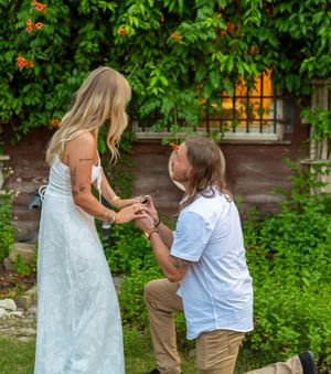 A romantic proposal moment takes place in a lush garden setting with greenery and flowers. Proposal Engagement session Fort Worth Dallas