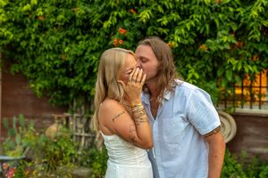 A couple shares a romantic moment on a garden bench surrounded by lush green foliage. Proposal Fort Worth Dallas Texas. Engagement