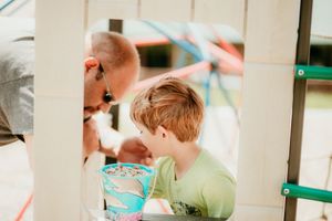 A child in a green shirt leans over a counter in a bright indoor setting, captured in a candid moment.
