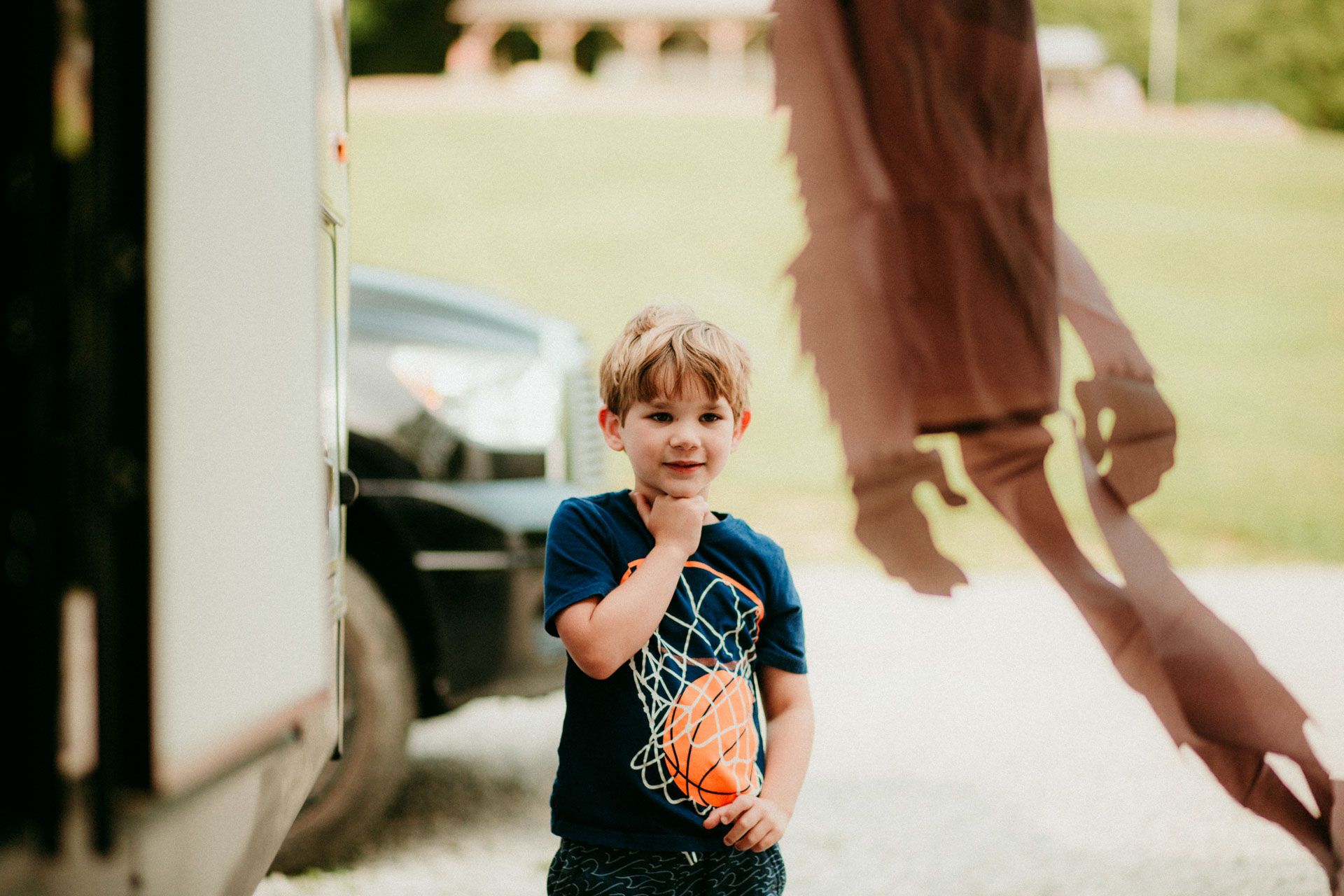 A young child in a blue t-shirt eats an ice cream cone outdoors on a sunny day.
