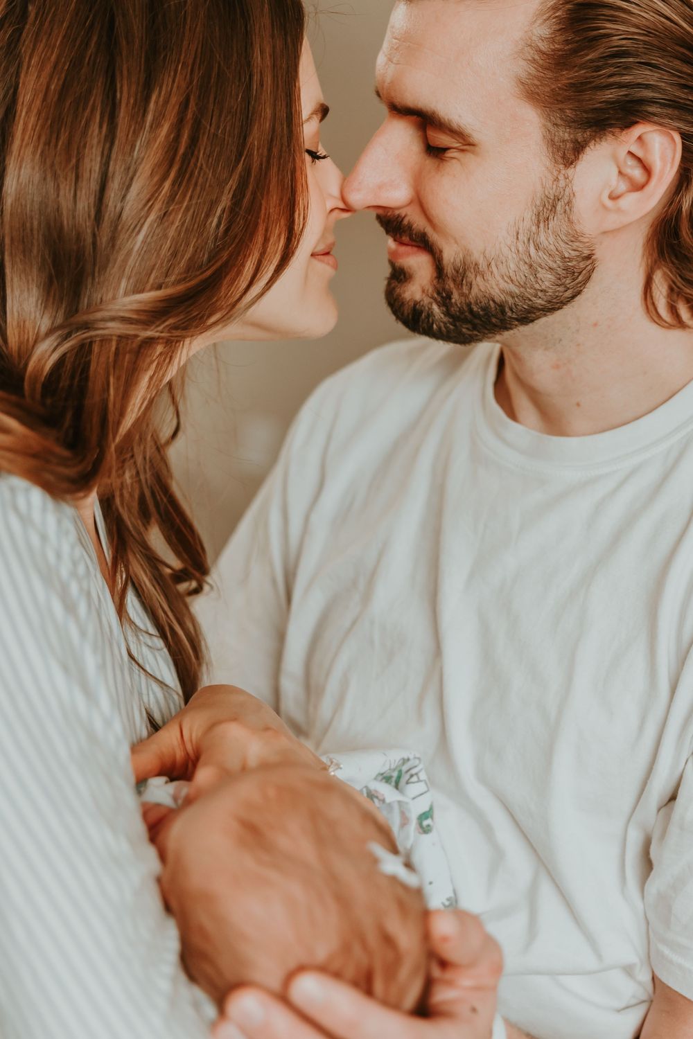 A couple in white sweaters sharing an intimate moment while bathed in warm sepia tones.