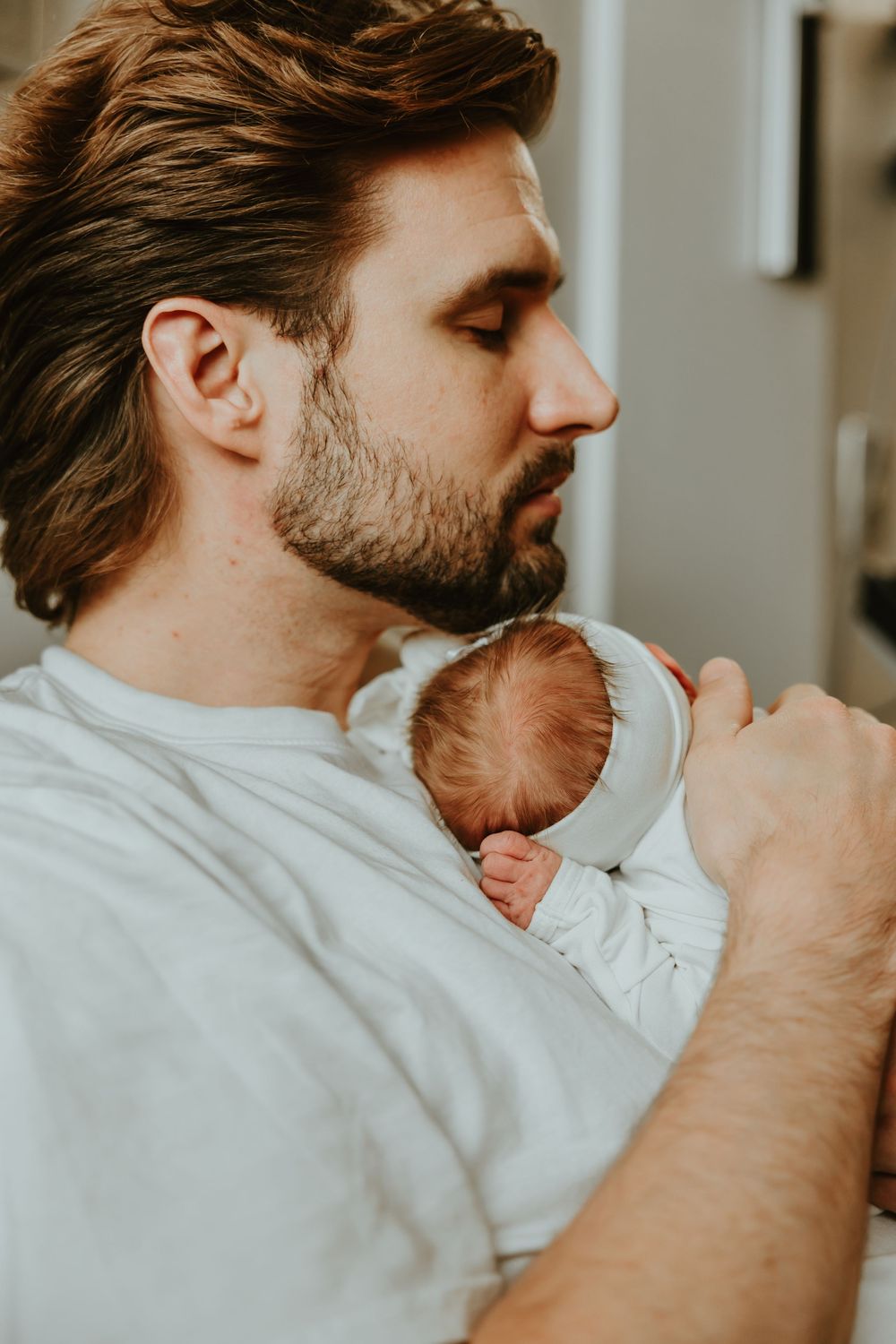 Baby being held against chest in tender moment with soft lighting.
