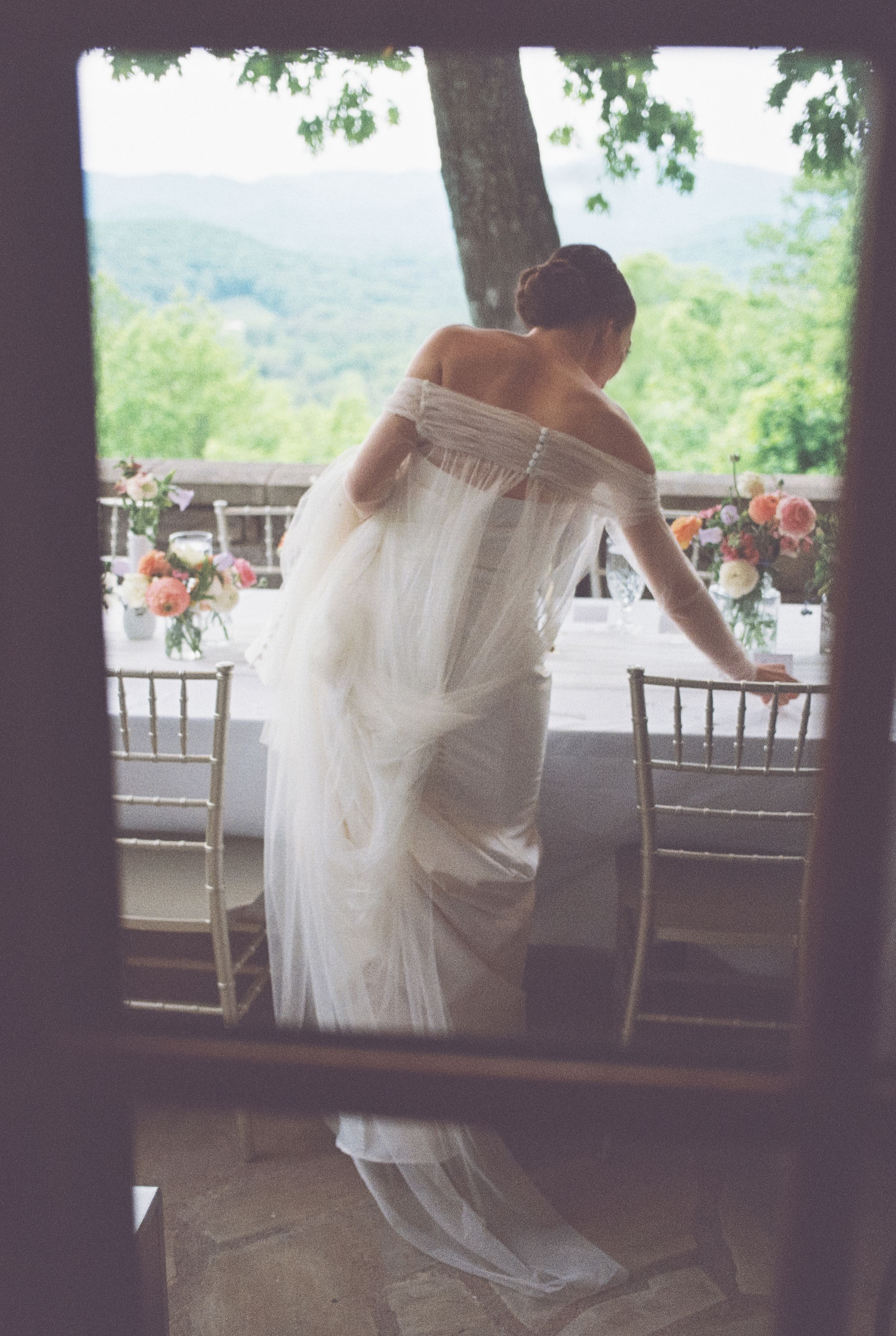 A romantic couple embraces near windows with scenic mountain views during an indoor wedding celebration.