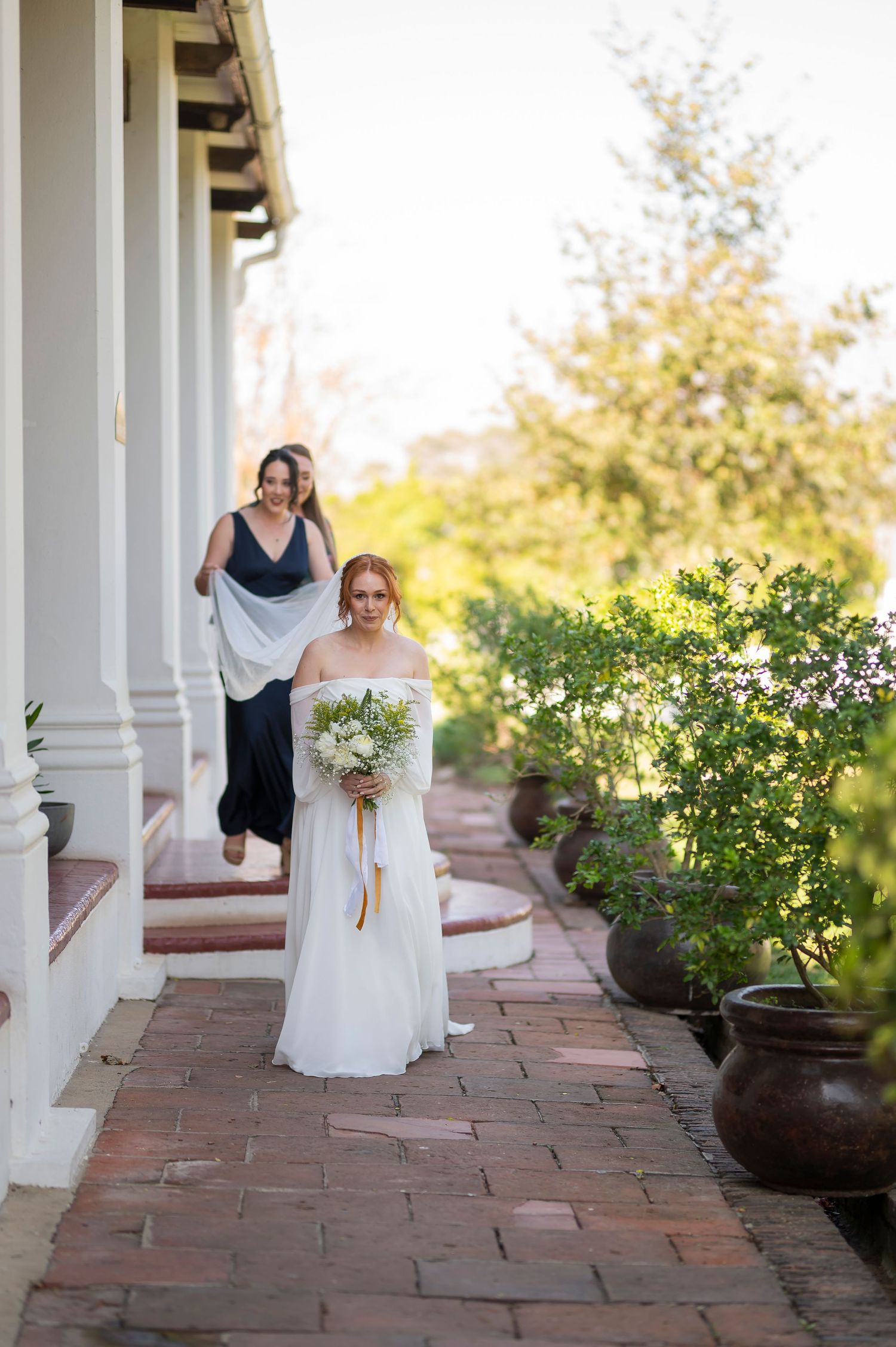 White columned porch with brick pathway leading to garden setting.