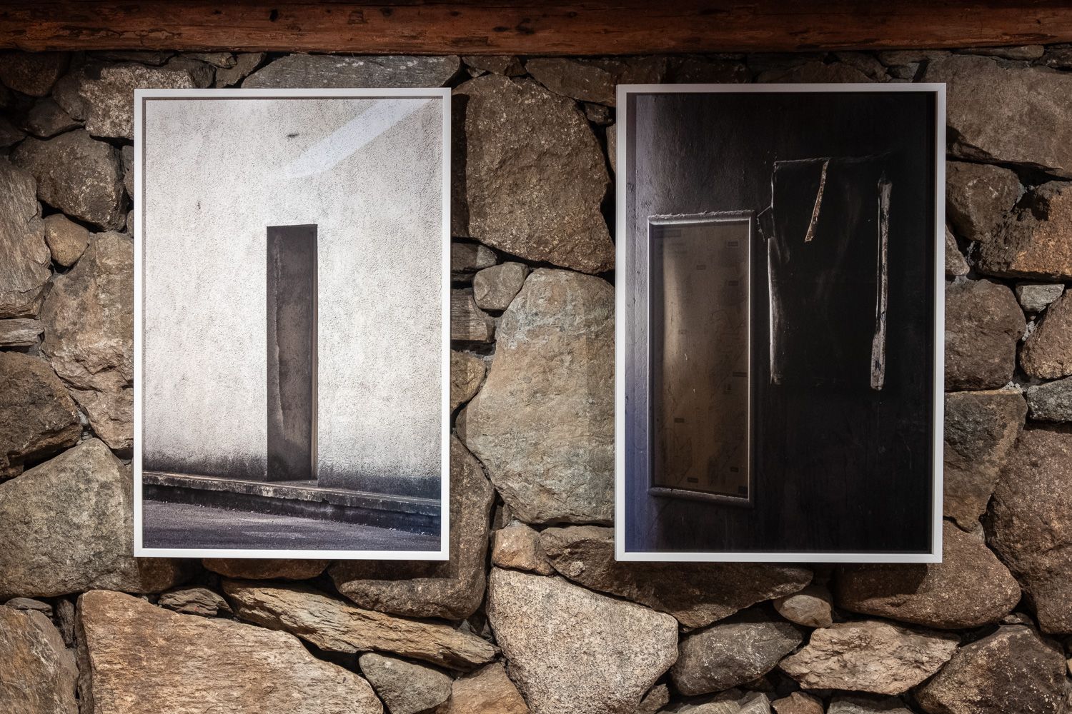 Interior room with exposed wooden beams and framed artwork on white walls.