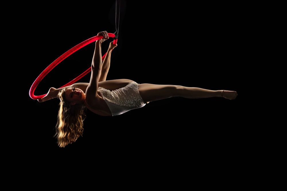 A sequence of a gymnast performing a high-skill back flip maneuver against a black background with dynamic motion blur.