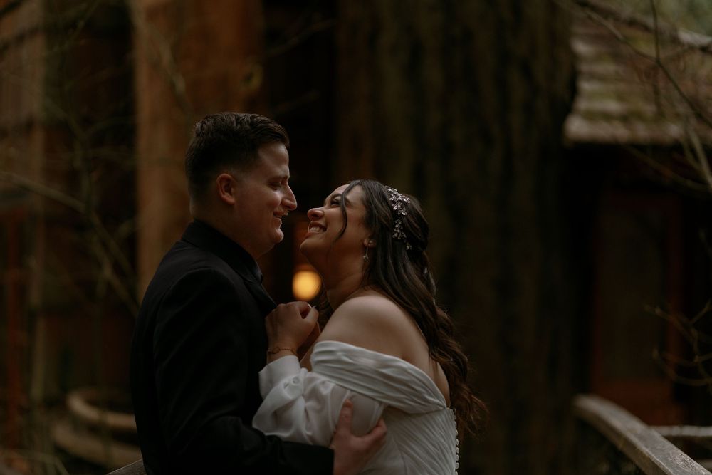 Couple shares intimate romantic moment in dimly lit forest setting during wedding celebration.
