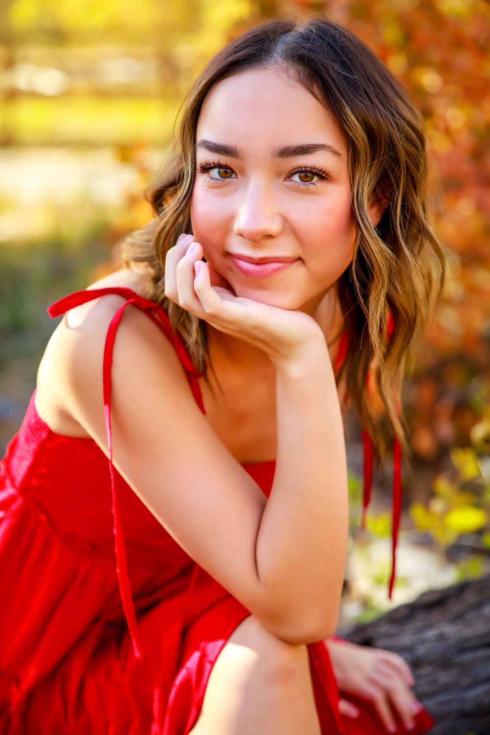 Close up portrait in red dress with gentle smile against autumn background.