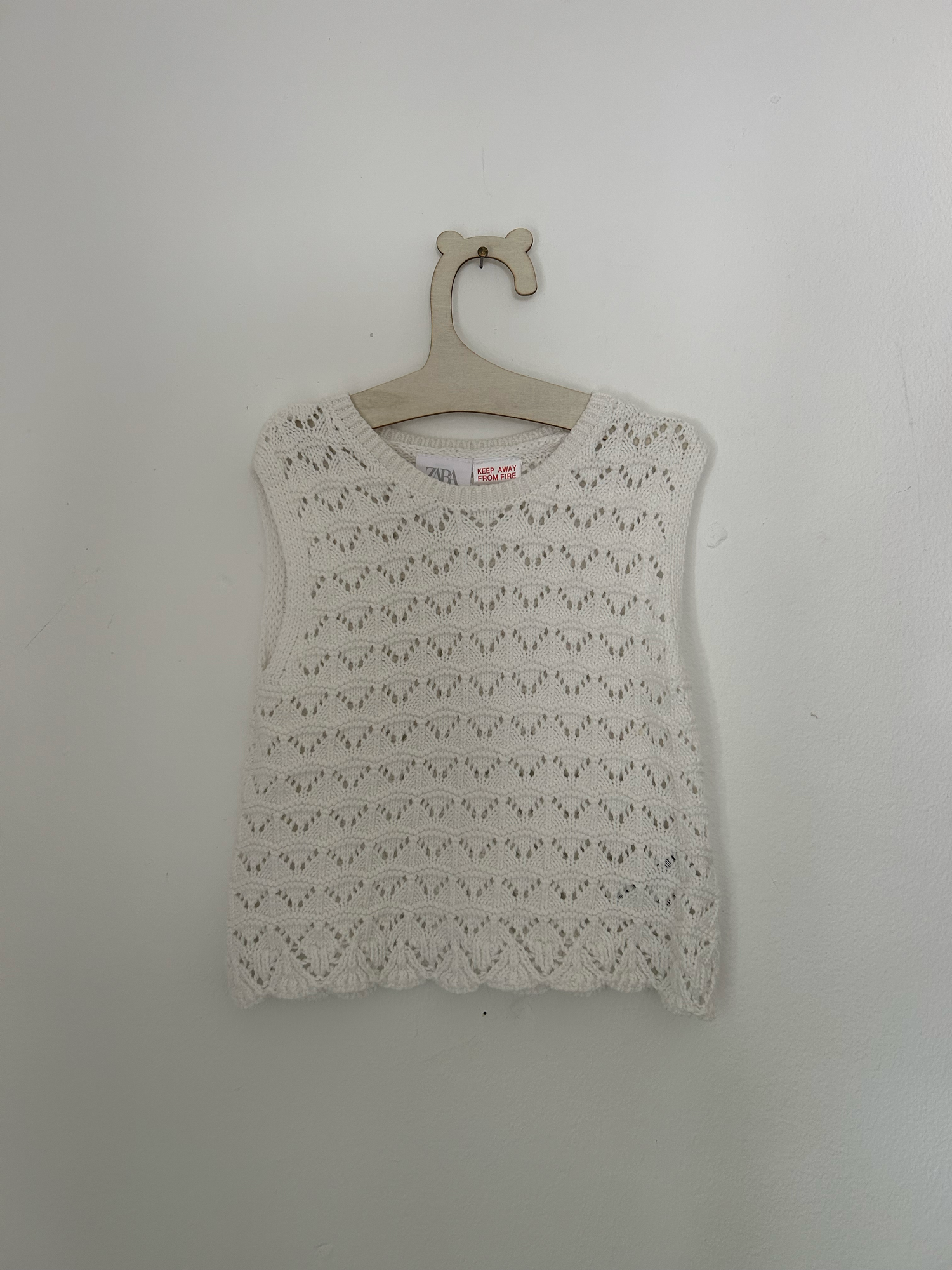White baby romper with delicate pink embroidered floral design and ruffle details on straps.