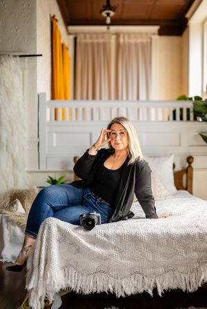 Camera and cozy room scene with white bedspread, yellow curtain, and wood ceiling details.