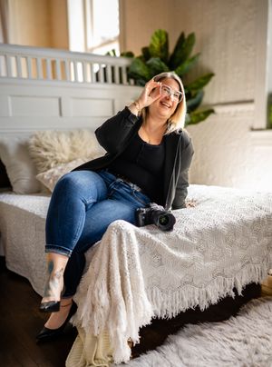 A relaxed lifestyle photo showing a person in black sweater and jeans lounging on a white couch with a camera nearby.