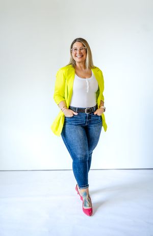 Stylish casual outfit featuring bright yellow blazer, white top, blue jeans and pink heels against white background.