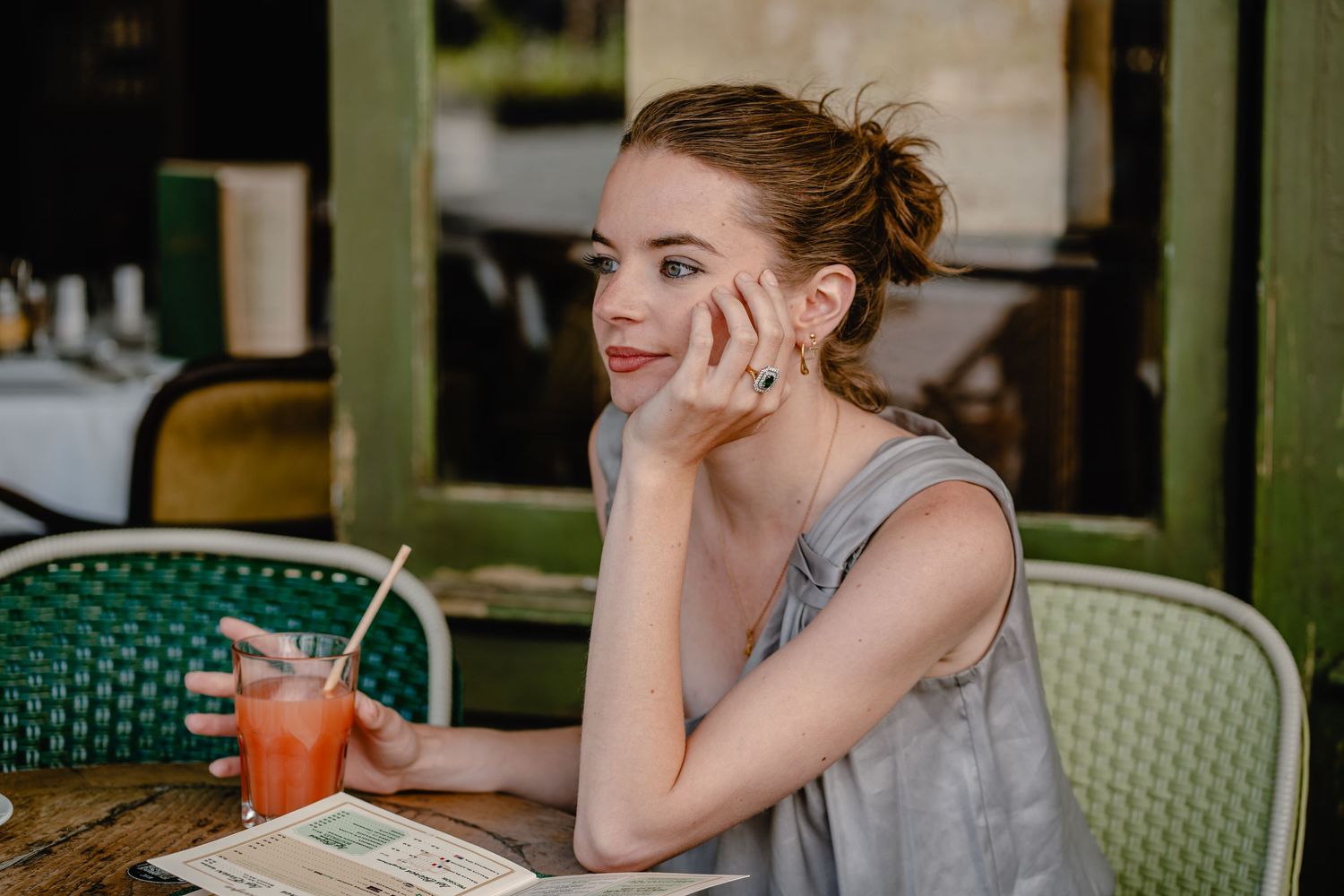 Two people enjoying drinks and conversation at a cafe with green chairs.