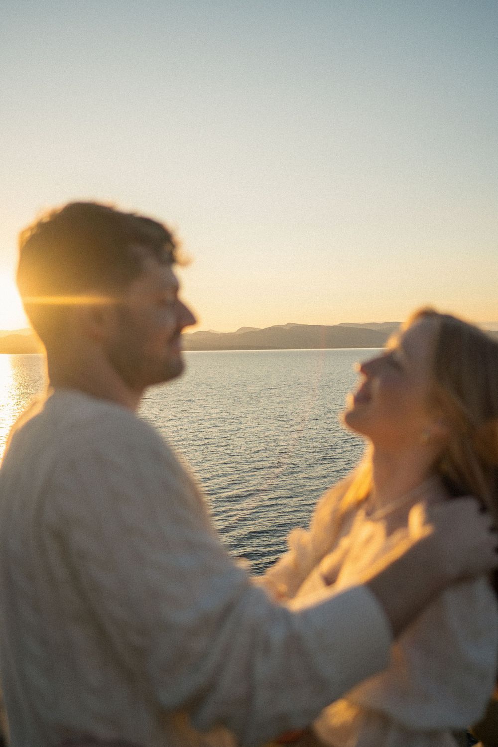 A couple shares an intimate moment at sunset by the ocean.