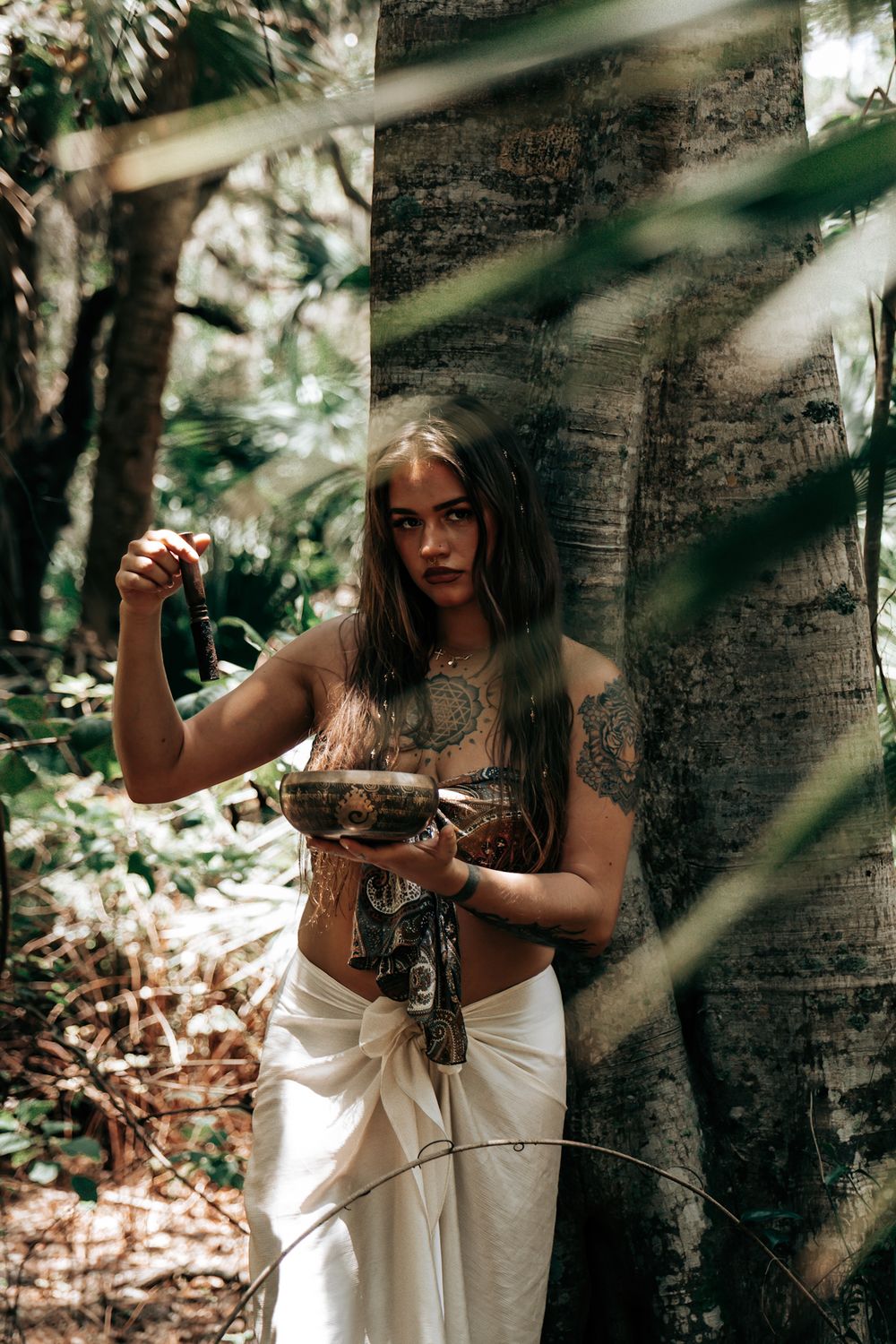 Artistic portrait in a forest setting with dramatic natural lighting.