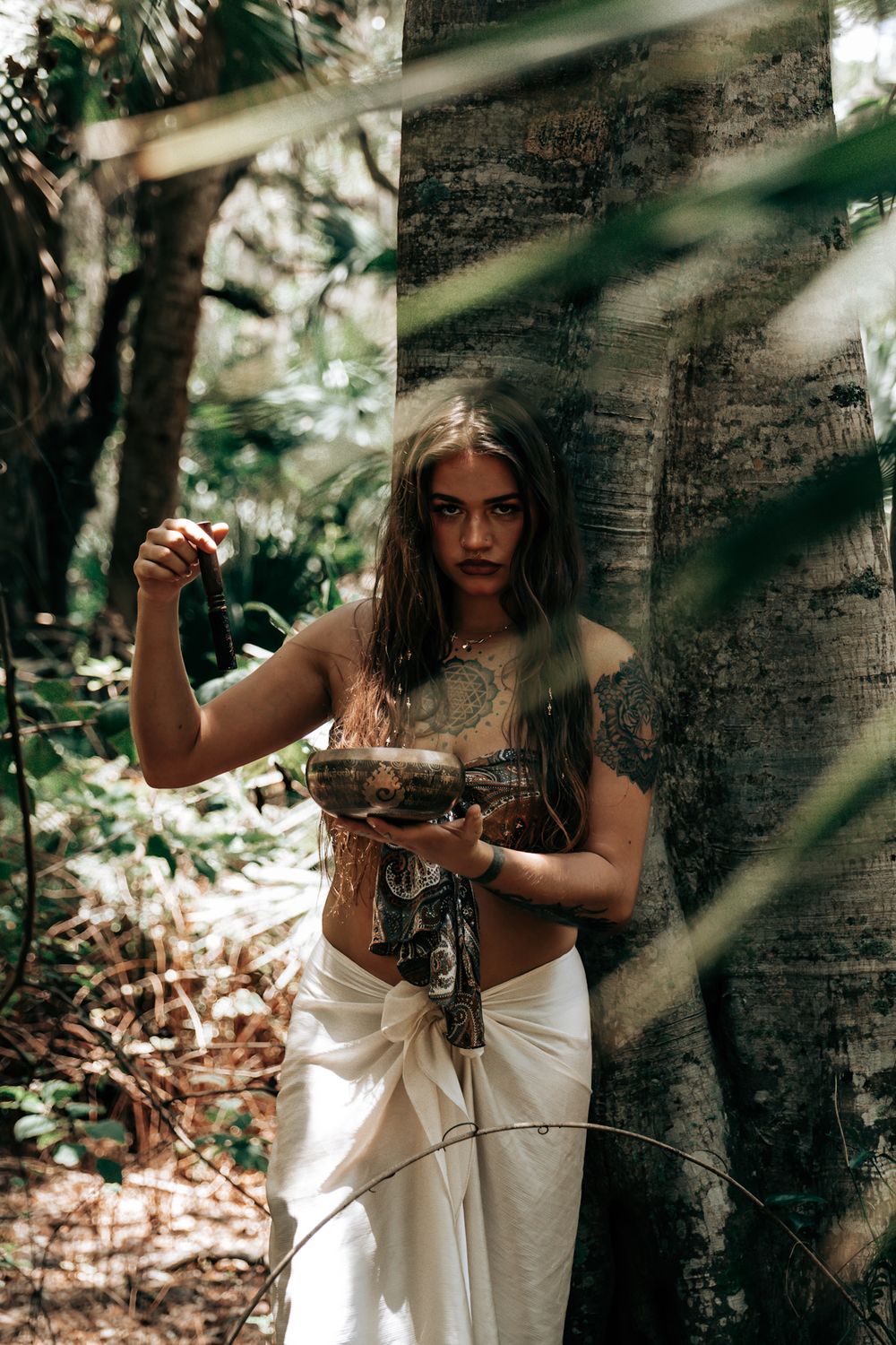Dramatic forest photoshoot with natural sunlight filtering through trees.